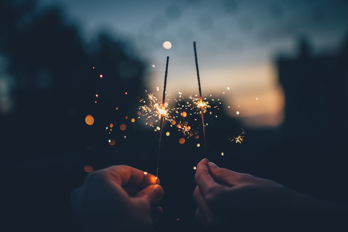 Sparklers held up against a night sky, representing July 4th fireworks, PM2.5 air pollution, and how kale's sulforaphane, quercetin, and vitamin C protect your lungs during fireworks season